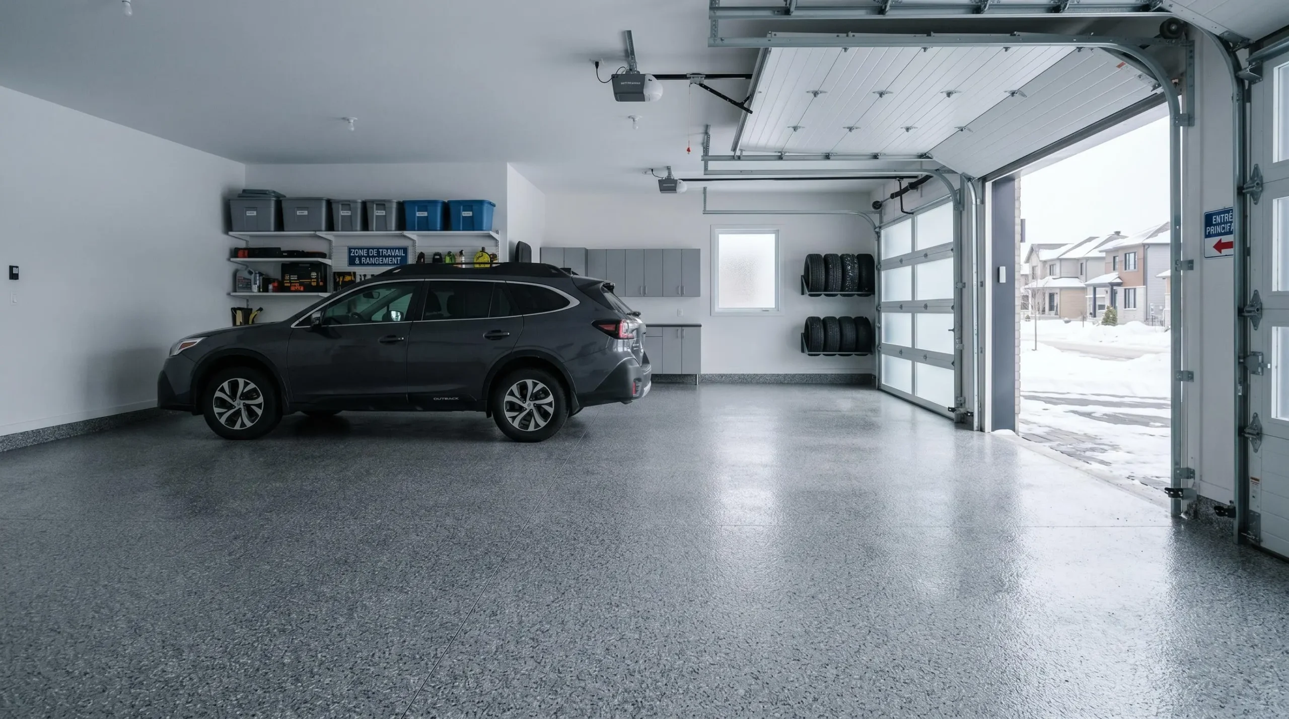 Garage résidentiel québécois moderne avec plancher en revêtement époxy-polyuréa gris à flocons granit, surface brillante et impeccable, véhicule récent stationné, lumière naturelle hivernale douce
